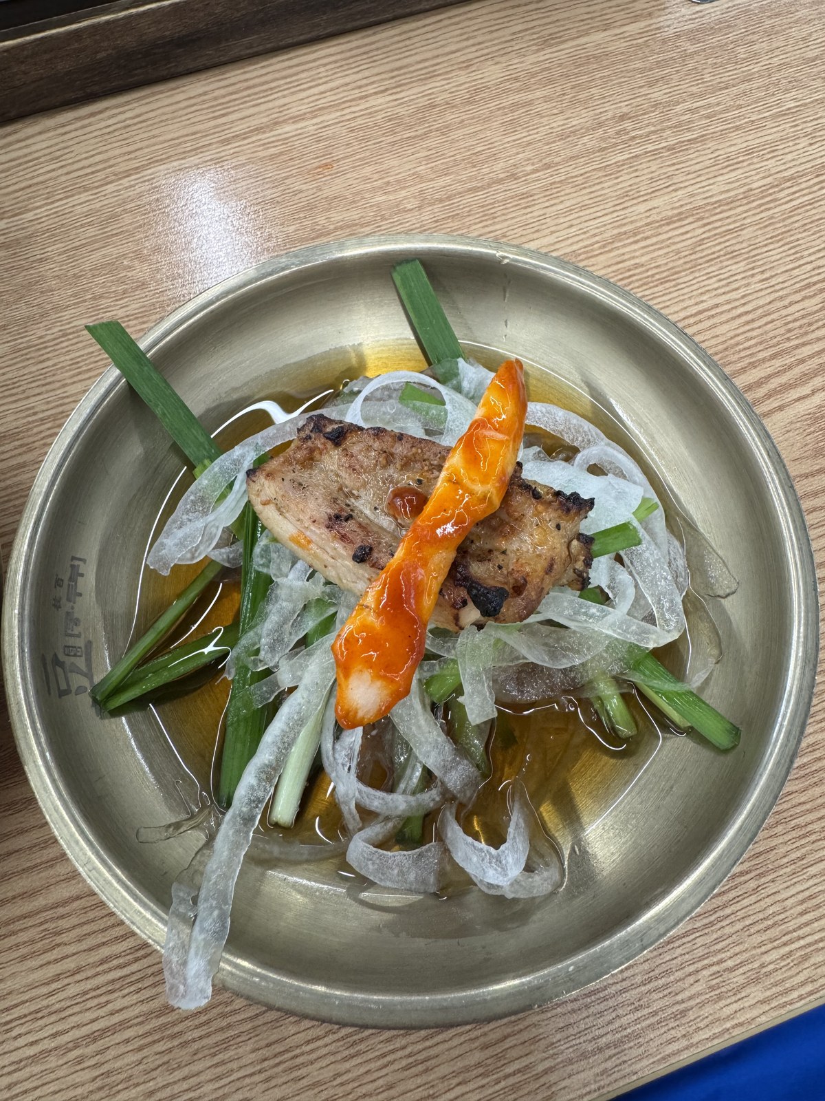 간장에 절인 양파채 위에 닭갈비와 더덕을 올린 놋그릇