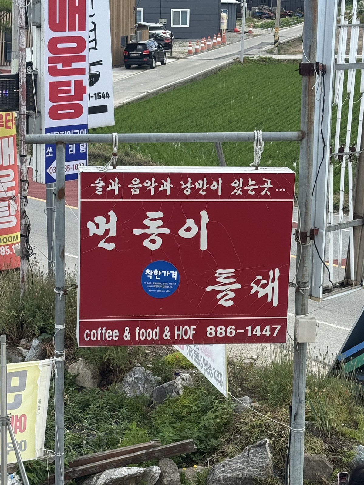 도로변에 세워진 먼동이 틀때 빨간 간판과 논밭