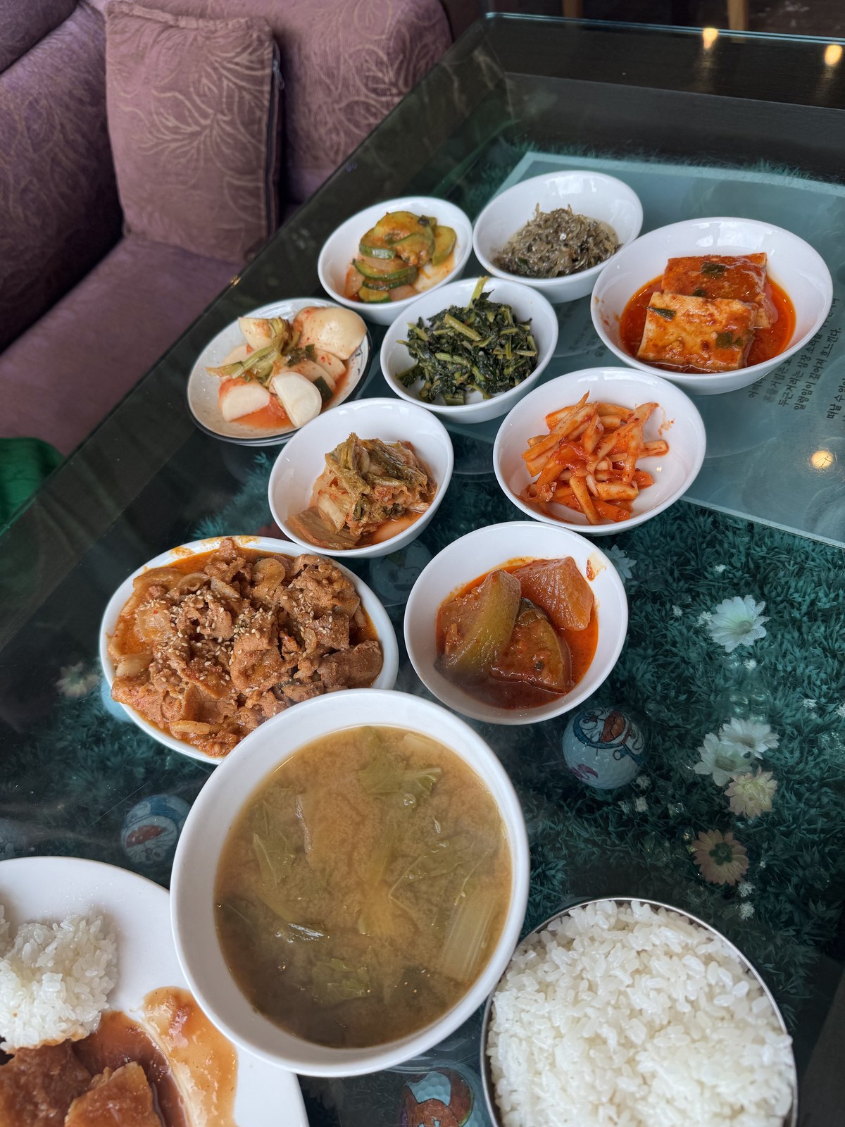 반찬 여덟 종지와 국, 밥이 유리 테이블에 차려진 모습