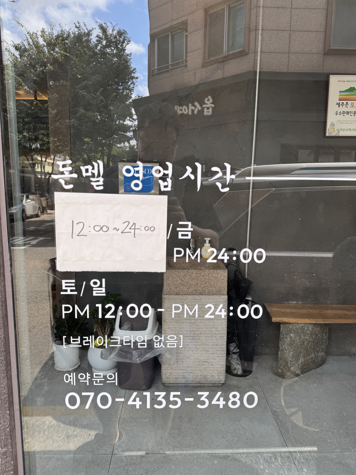 돈멜 보정직영점 창에 붙은 영업시간 안내