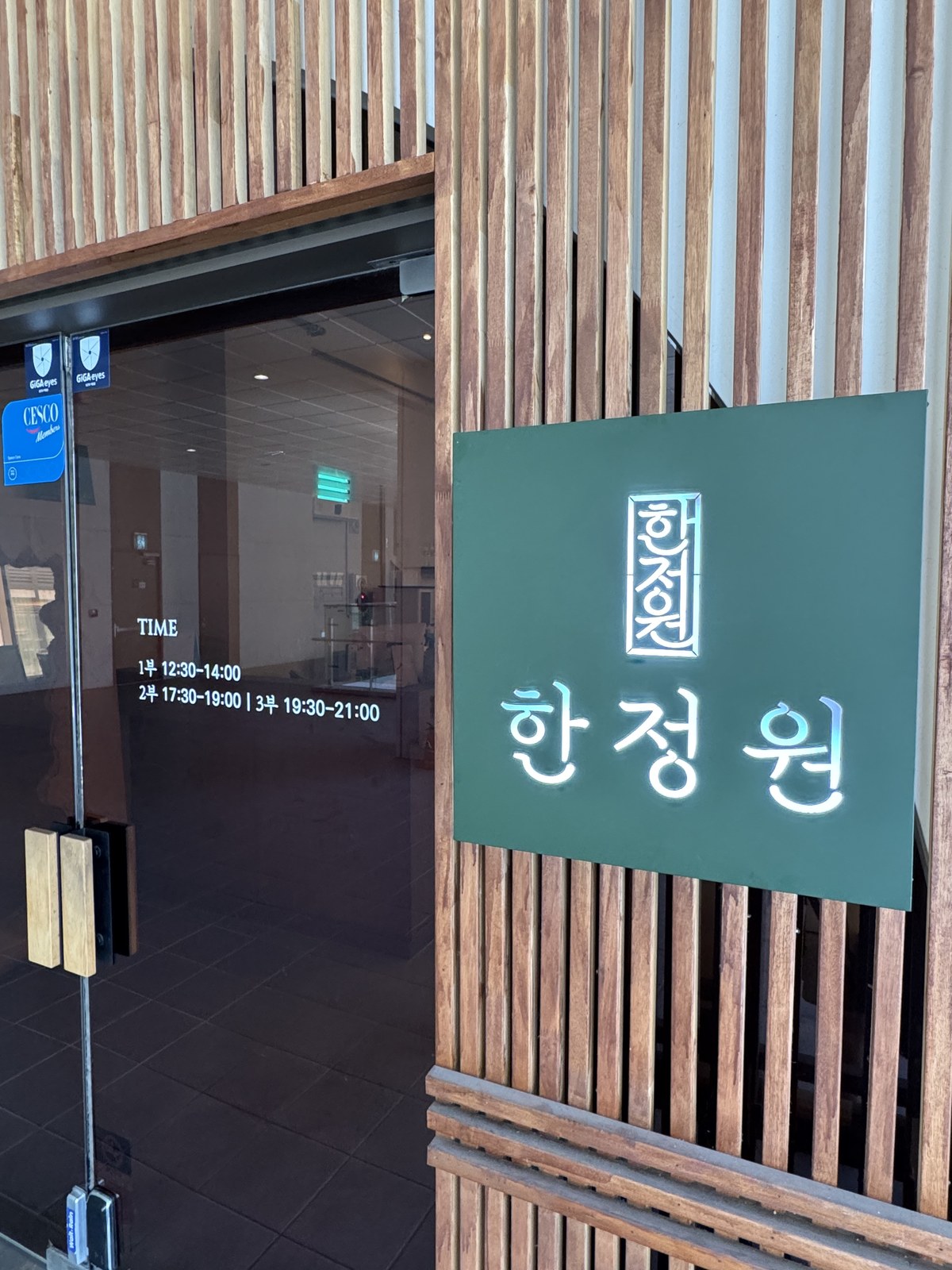한정원 입구 — 나무 살 벽에 걸린 초록 간판