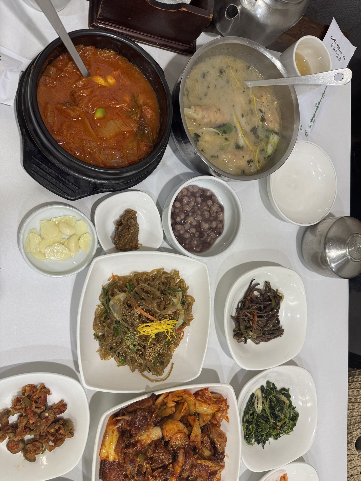 얼큰한 김치찌개와 만둣국 냄비, 잡채와 마늘 등 반찬이 오른 한 상