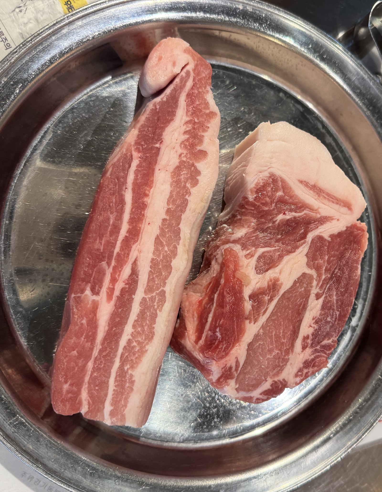 접시에 나란히 놓인 두툼한 숙성 오겹살과 목살 생고기
