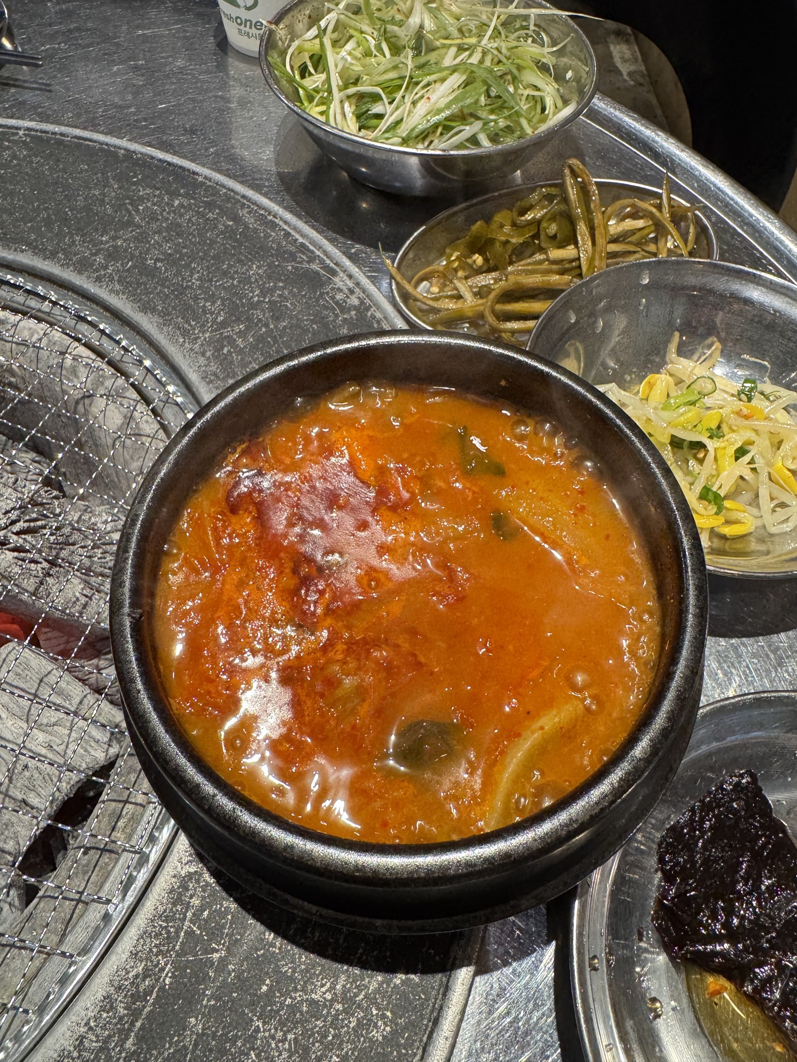 뚝배기에 빨갛게 끓는 김치찌개와 옆에 놓인 나물 반찬들