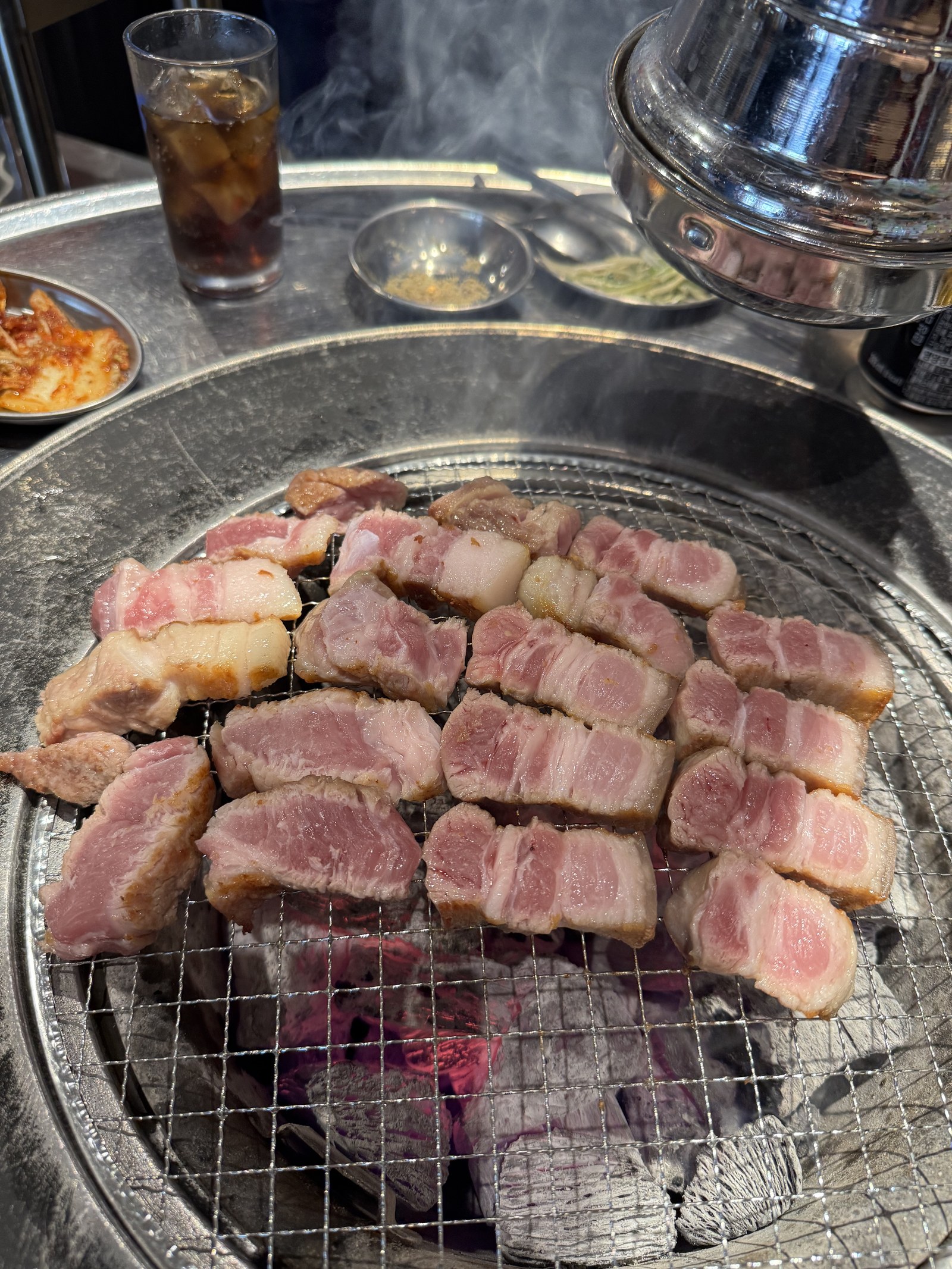 숯불 석쇠 위에 두툼한 숙성 고기가 가득 올라간 모습
